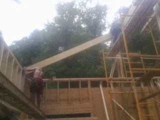 Carpenter raising a rafter beam on a new second story frame in Tyler