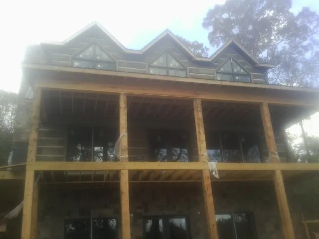 Dormers and porch framing on a large log home under construction — Roof Coating work by our crew in Tyler